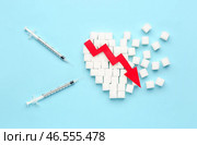 Сердце из сахара со стрелой, направленной вниз, и шприцами для инъекций инсулина на голубом фоне. Стоковое фото, фотограф Pixel_shot / Фотобанк Лори