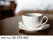 A white cup of hot tea or coffee on a wooden table in the interior of a hotel room. The concept of drinks and comfortable hotel accommodation. Стоковое фото, фотограф Photojuli / Фотобанк Лори