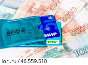 Банковские карты платёжной системы МИР в RFID защитных чехлах  - защита от считывания, мошенничества, кражи - на фоне пятитысячных купюр. Редакционное фото, фотограф Snezka / Фотобанк Лори