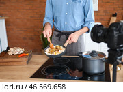 Молодой человек готовит вкусный рис во время записи видеоурока на кухне. Стоковое фото, фотограф Pixel_shot / Фотобанк Лори