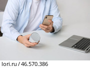 Мужчина подключает мобильный телефон к беспроводной портативной колонке на столе, крупным планом. Стоковое фото, фотограф Pixel_shot / Фотобанк Лори