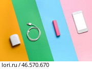 Внешний аккумулятор с мобильным телефоном, USB-кабелем и наушниками на цветном фоне. Стоковое фото, фотограф Pixel_shot / Фотобанк Лори