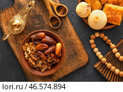 Вкусные восточные сладости с тасбихом и лампой Аладдина на темном фоне. Стоковое фото, фотограф Pixel_shot / Фотобанк Лори