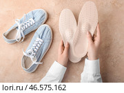 Женские руки с ортопедическими стельками и кроссовками на бежевом фоне. Стоковое фото, фотограф Pixel_shot / Фотобанк Лори