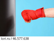 Мужская рука с красным боксерским бинтом и ударным мешком на синем фоне. Стоковое фото, фотограф Pixel_shot / Фотобанк Лори