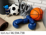 Боксёрские перчатки, баскетбольный мяч, футбольный мяч, бутылка с водой и кроссовки на кафельном полу. Стоковое фото, фотограф Pixel_shot / Фотобанк Лори