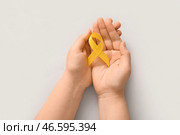 Женские руки с жёлтой лентой на светлом фоне. Концепция саркомы. Стоковое фото, фотограф Pixel_shot / Фотобанк Лори