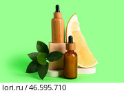 Красивое композиционное изображение с флаконами косметических продуктов, листьями и кусочком свежего помело на зелёном фоне, крупным планом. Стоковое фото, фотограф Pixel_shot / Фотобанк Лори