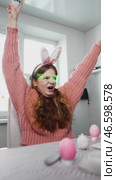 Happy gamer girl in bunny ears and LED glasses enjoys gaming in festive Easter-themed room. She holds controller, celebrating victory while surrounded by Easter eggs and decorations. Стоковое видео, видеограф Енваев Андрей / Фотобанк Лори