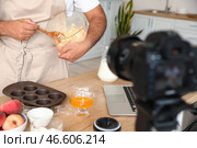 Красивый мужчина готовит кексы с персиками и записывает видеоурок на кухне. Стоковое фото, фотограф Pixel_shot / Фотобанк Лори