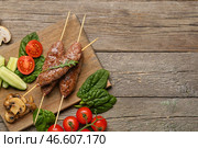 Доска для шашлыка с вкусным люля-кебабом и овощами на деревянном фоне. Стоковое фото, фотограф Pixel_shot / Фотобанк Лори