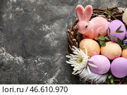 Гнездышко с расписными пасхальными яйцами, кроликом и цветами на сером фоне. Стоковое фото, фотограф Pixel_shot / Фотобанк Лори