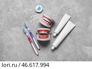 Модель челюстей с брекетами, зубной нитью, зубными щетками и пастой на сером фоне. Стоковое фото, фотограф Pixel_shot / Фотобанк Лори
