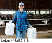 Milkmaid standing with plastic cans near open cowshed at dairy farm. Стоковое фото, фотограф Яков Филимонов / Фотобанк Лори