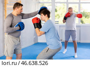 Guy in boxing gloves punching mitts in hands of instructor at self-defense class. Стоковое фото, фотограф Яков Филимонов / Фотобанк Лори