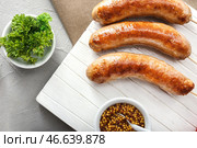 Деревянная доска с вкусными жареными колбасками на столе. Стоковое фото, фотограф Pixel_shot / Фотобанк Лори