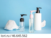 Бутылки дезинфицирующих средств и медицинских масок на цветном фоне. Стоковое фото, фотограф Pixel_shot / Фотобанк Лори