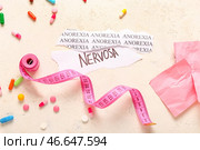 Кусочки бумаги с текстом ANOREXIA NERVOSA, таблетки и измерительная лента на белом фоне. Стоковое фото, фотограф Pixel_shot / Фотобанк Лори