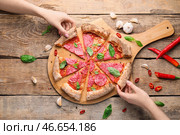 Женщины берут кусочки вкусной пиццы с доски на стол. Стоковое фото, фотограф Pixel_shot / Фотобанк Лори