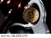 Физическая монета криптовалюты биткойн, судейский молоток и наручники. Стоковое фото, фотограф Сергей Елагин/Бизнес Online / ТАСС / Фотобанк Лори