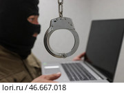 Интернет-мошенник с ноутбуком и наручники. Стоковое фото, фотограф Сергей Булкин/NEWS.ru / ТАСС / Фотобанк Лори