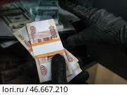 Банкноты из вскрытого сейфа в руках вора в черных кожаных перчатках. Стоковое фото, фотограф Сергей Булкин/NEWS.ru / ТАСС / Фотобанк Лори