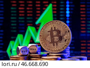 Кубики с надписями "buy" ("купить") и "sell" ("продать") и монета криптовалюты биткойн на фоне зеленой стрелки, указывающей вверх. Стоковое фото, фотограф Сергей Елагин/Бизнес Online / ТАСС / Фотобанк Лори