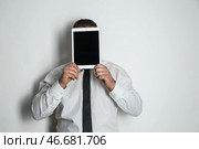 Бизнесмен скрывается лицо за планшетным компьютером на светлом фоне. Стоковое фото, фотограф Pixel_shot / Фотобанк Лори