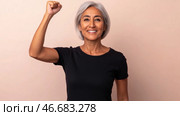 Middle aged latin american woman with raised fist of empowerment, strength and women solidarity, International Womens Day concept. Стоковое AI-изображение, AI-художник Анастасия Золотницкая / Фотобанк Лори