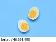 Половинки вкусного отваренного яйца на голубом фоне. Стоковое фото, фотограф Pixel_shot / Фотобанк Лори