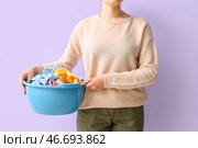 Женщина держит пластиковую моеку с грязной бельем на лиловом фоне. Стоковое фото, фотограф Pixel_shot / Фотобанк Лори
