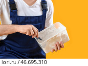 Мужчина-декоратор с шпателем и гипсом на жёлтом фоне, крупным планом. Стоковое фото, фотограф Pixel_shot / Фотобанк Лори