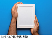Мужчина держит пустую фоторамку на голубом фоне. Стоковое фото, фотограф Pixel_shot / Фотобанк Лори