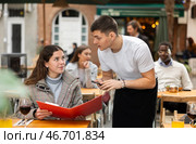 On open area of cafe, guy waiter communicates with girl customer, accepts order. Стоковое фото, фотограф Яков Филимонов / Фотобанк Лори