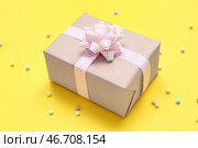 Подарочная коробка с розовым бантом в клетку и бусинами на желтом фоне. Стоковое фото, фотограф Pixel_shot / Фотобанк Лори