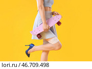 Юная пин-ап девушка со скейтбордом на желтом фоне. Стоковое фото, фотограф Pixel_shot / Фотобанк Лори
