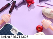 Рамка из весов с яблоком, кроссовками и спортивным инвентарем на сиреневом фоне. Концепция похудения. Стоковое фото, фотограф Pixel_shot / Фотобанк Лори