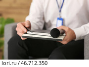 Мужчина-репортер с микрофоном и блокнотом, сидящий в кресле в студии, крупный план. Стоковое фото, фотограф Pixel_shot / Фотобанк Лори