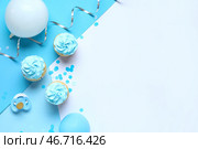 Вкусные капкейки с воздушными шарами, соской и декором на синем фоне. Концепция вечеринки по случаю раскрытия пола. Стоковое фото, фотограф Pixel_shot / Фотобанк Лори