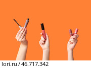 Женские руки с тушью и губными помадами на оранжевом фоне. Стоковое фото, фотограф Pixel_shot / Фотобанк Лори