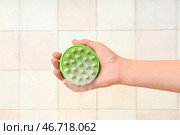 Женская рука с силиконовой щеткой для массажа головы и шампунем на фоне белой плитки. Стоковое фото, фотограф Pixel_shot / Фотобанк Лори