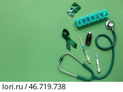 Композиция с зеленой лентой и медицинскими принадлежностями на цветном фоне. Национальный месяц осведомленности о церебральном параличе. Стоковое фото, фотограф Pixel_shot / Фотобанк Лори
