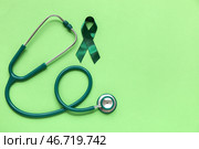 Атласная зеленая лента и стетоскоп на цветном фоне. Национальный месяц осведомленности о церебральном параличе. Стоковое фото, фотограф Pixel_shot / Фотобанк Лори