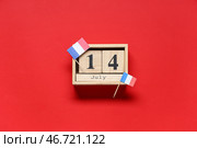 Кубический календарь с датой 14 июля и французскими флагами на красном фоне. Празднование Дня взятия Бастилии. Стоковое фото, фотограф Pixel_shot / Фотобанк Лори