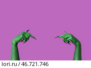 Зеленые руки ведьмы, указывающие на что-то на фиолетовом фоне. Празднование Хэллоуина. Стоковое фото, фотограф Pixel_shot / Фотобанк Лори