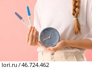 Женщина с тестами на беременность и будильником на розовом фоне. Крупный план. Стоковое фото, фотограф Pixel_shot / Фотобанк Лори