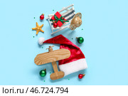 Шапка Санты, игрушечный шезлонг, морская звезда и деревянный самолет на синем фоне. Концепция рождественских каникул. Стоковое фото, фотограф Pixel_shot / Фотобанк Лори