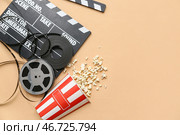 Хлопушка для кино с попкорном и кинолентами на бежевом фоне. Стоковое фото, фотограф Pixel_shot / Фотобанк Лори