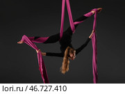 Girl performing aerial silk acrobatics with pink fabric in a dark studio. Стоковое фото, фотограф Гурьянов Андрей / Фотобанк Лори