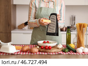 Женщина натирает сыр на пасту за столом на кухне, крупный план. Стоковое фото, фотограф Pixel_shot / Фотобанк Лори